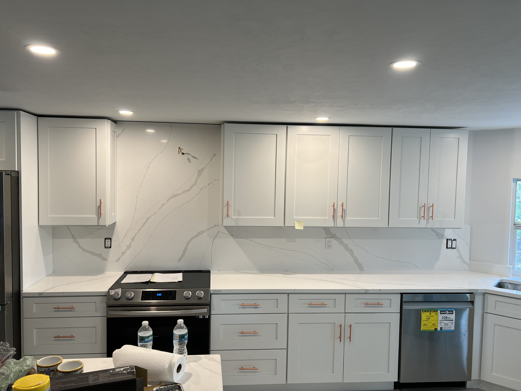 A kitchen with white cabinets and marble countertops.