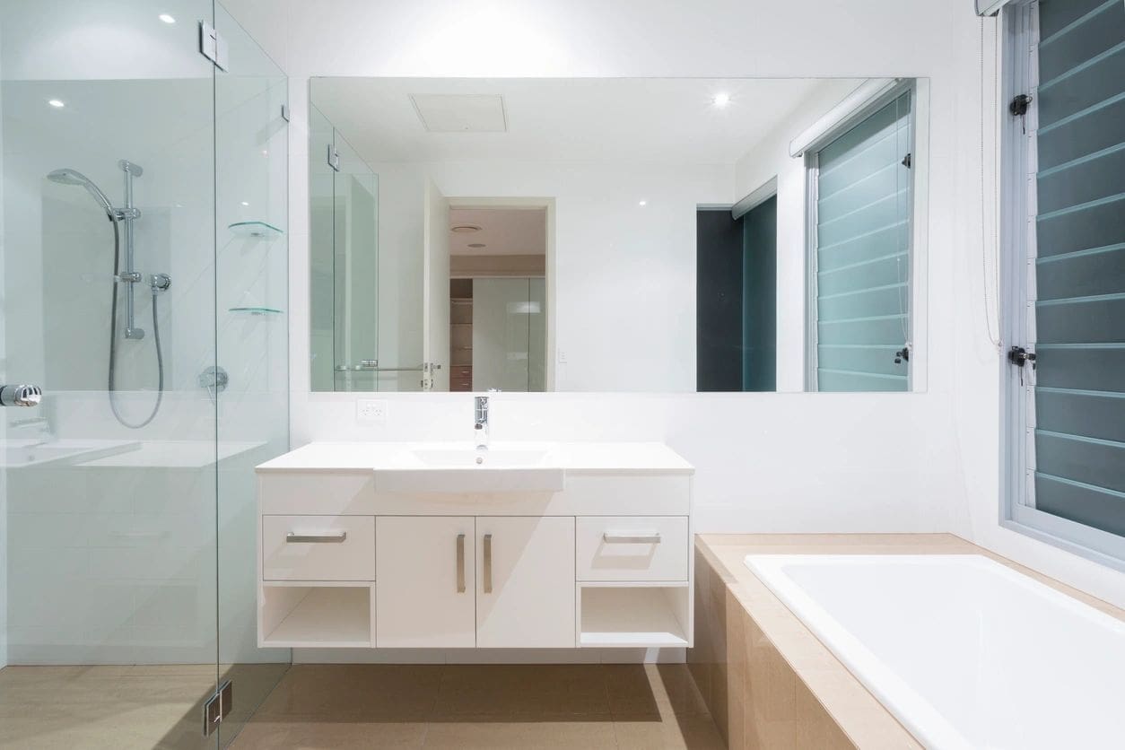 A bathroom with white cabinets and a large mirror.